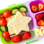 Colorful bento box filled with creative lunch ideas for kids including fruit, vegetables, and fun-shaped sandwiches
